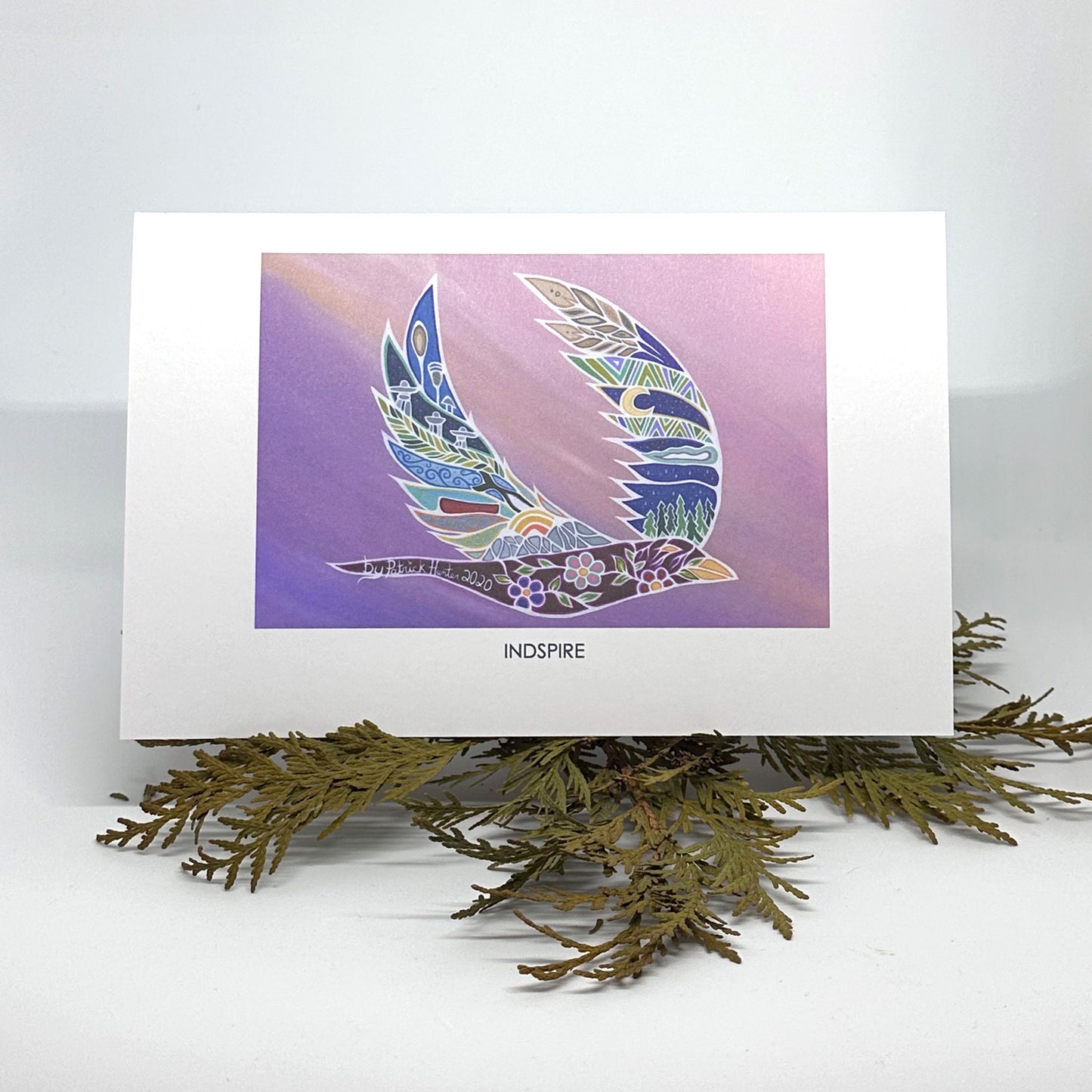 Patrick Hunter's painting in woodland art style, Indspire, as a greeting card standing open on boughs of cedar.