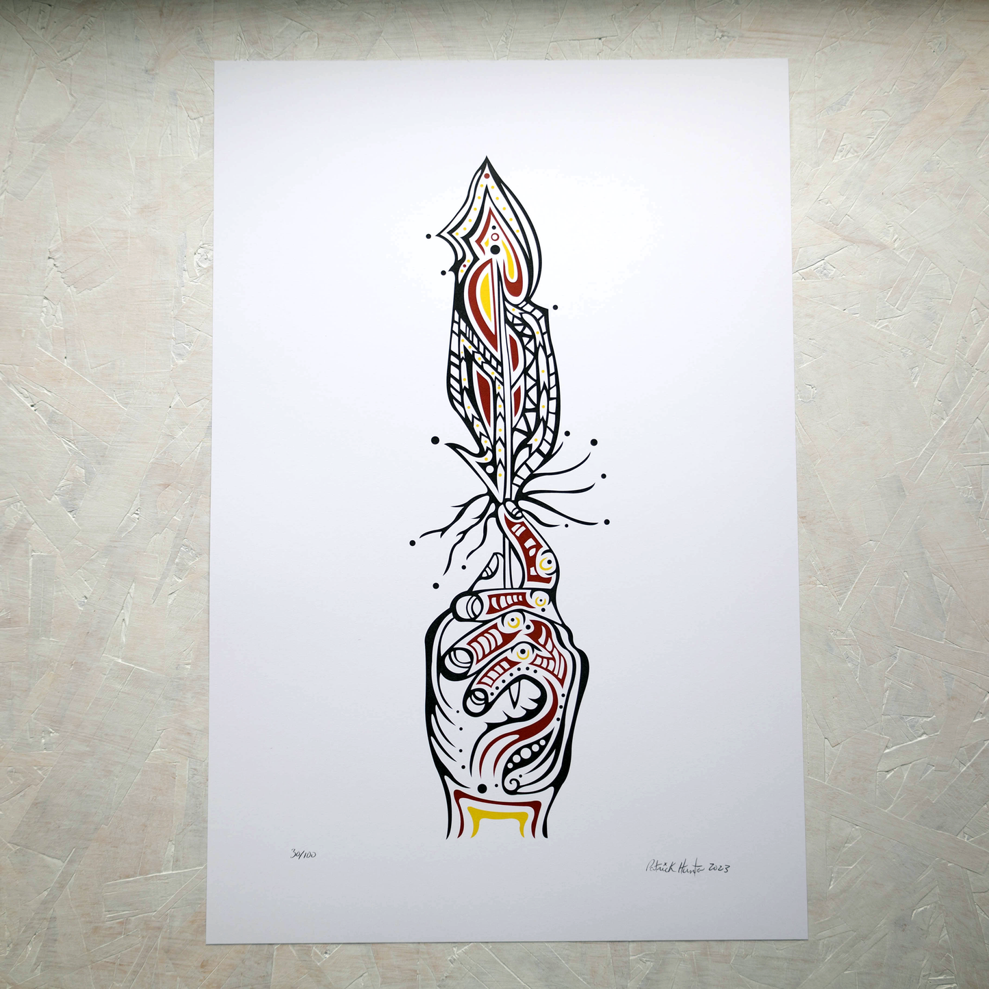 Print of Patrick Hunter's painting of a hand holding a feather upright, black, red, and gold on white, woodland art style.
