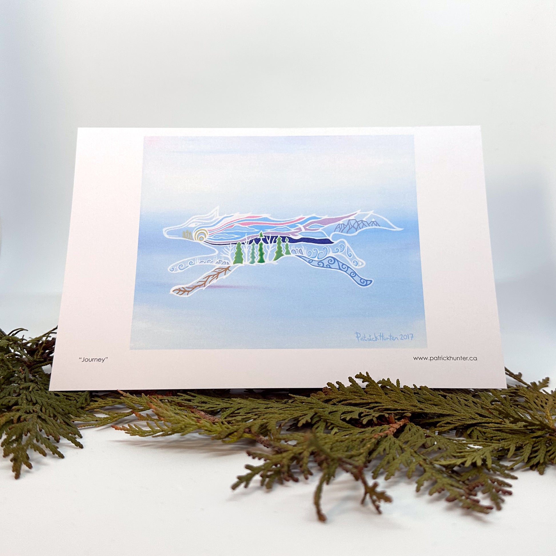 Patrick's artwork, Journey, as a greeting card, standing on cedar boughs.