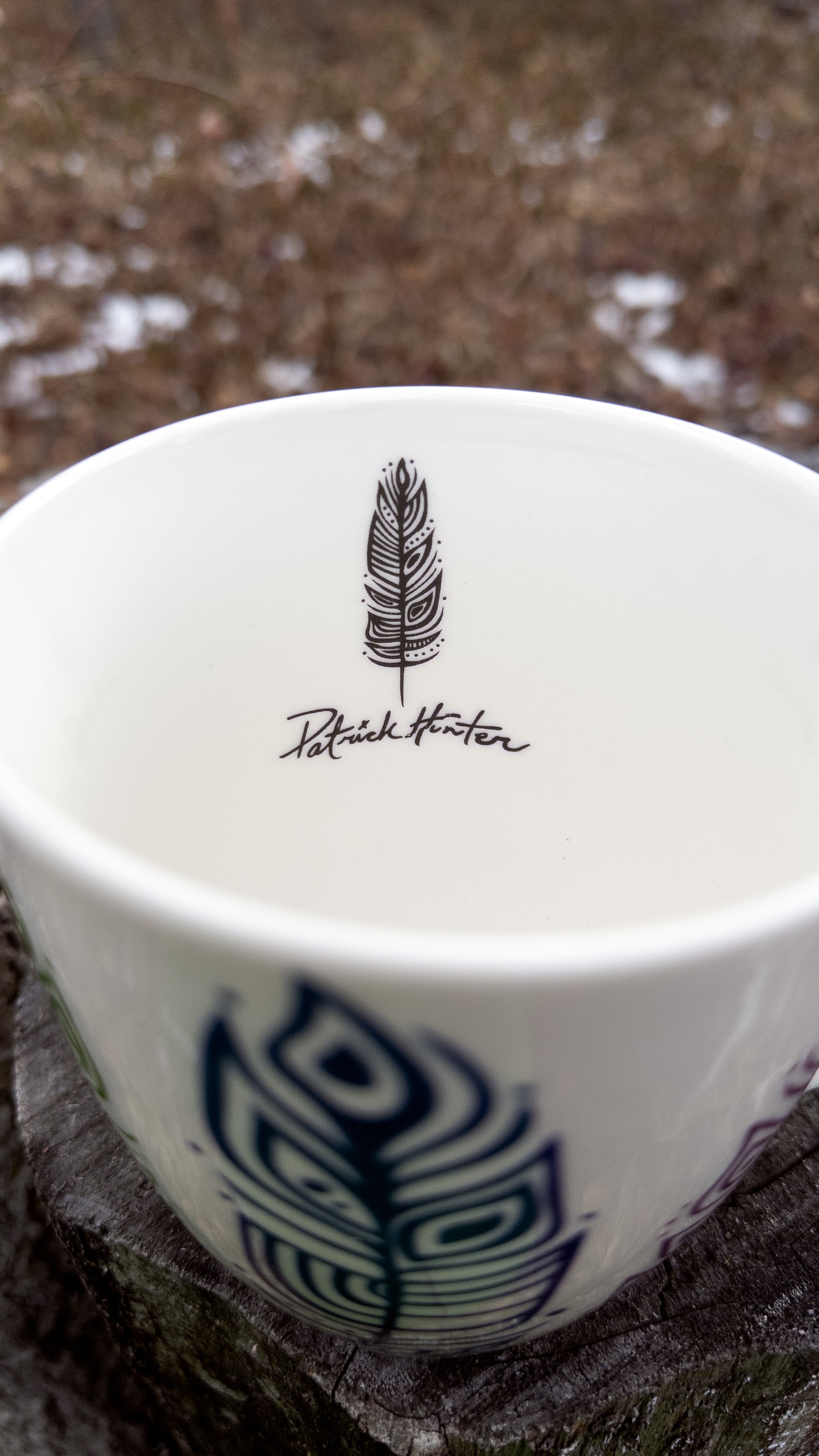 A glimpse inside the Pride Feathers mug that shows Patrick Hunter's signature and signature eagle feather on the inside just below the rim.