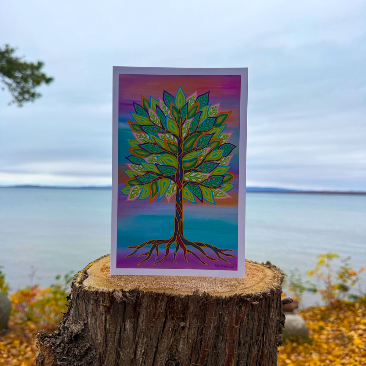A greeting card with Patrick's woodland art style painting of a colourful tree with outstretched roods against a multicolour background.
