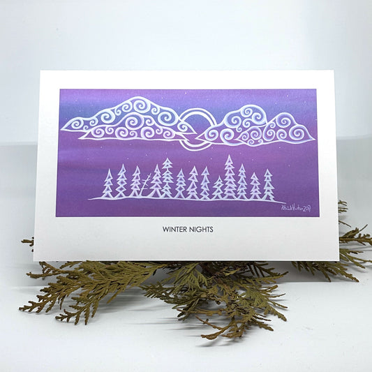 Patrick's painting of winter nights in woodland art style as a greeting card resting on cedar boughs.