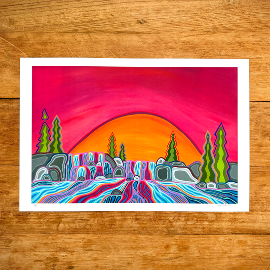 A print of Patrick Hunter's painting, Cascades, in Woodland Art style, against a wood grain backdrop. The print contains vibrant colours as cascading waterfalls run to the foreground, with trees, rocks surrounding. A large orange sun rests behind the cascades, against a bright sunset sky.